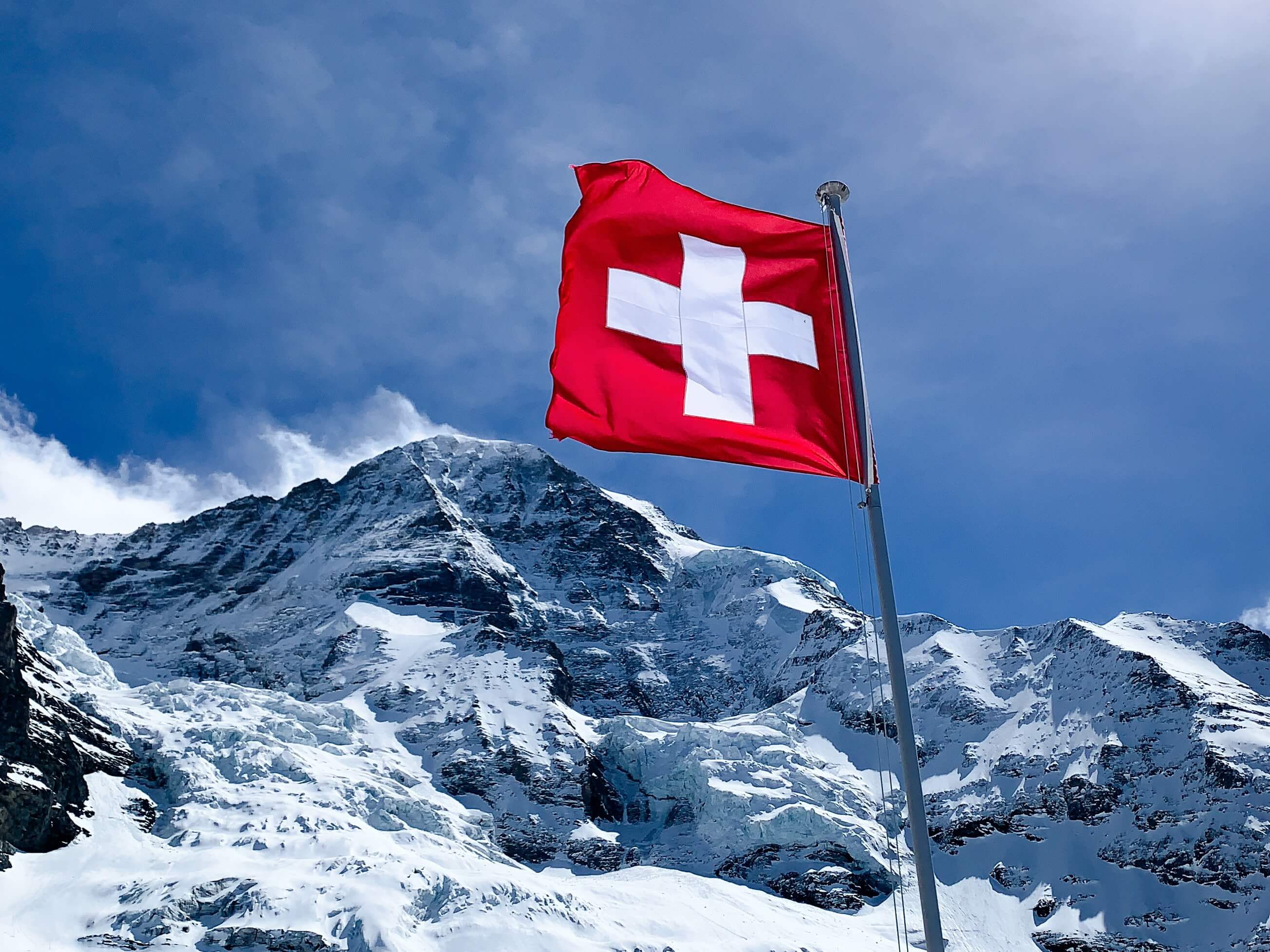 Švicarska zastava plapola v zasneženih gorah